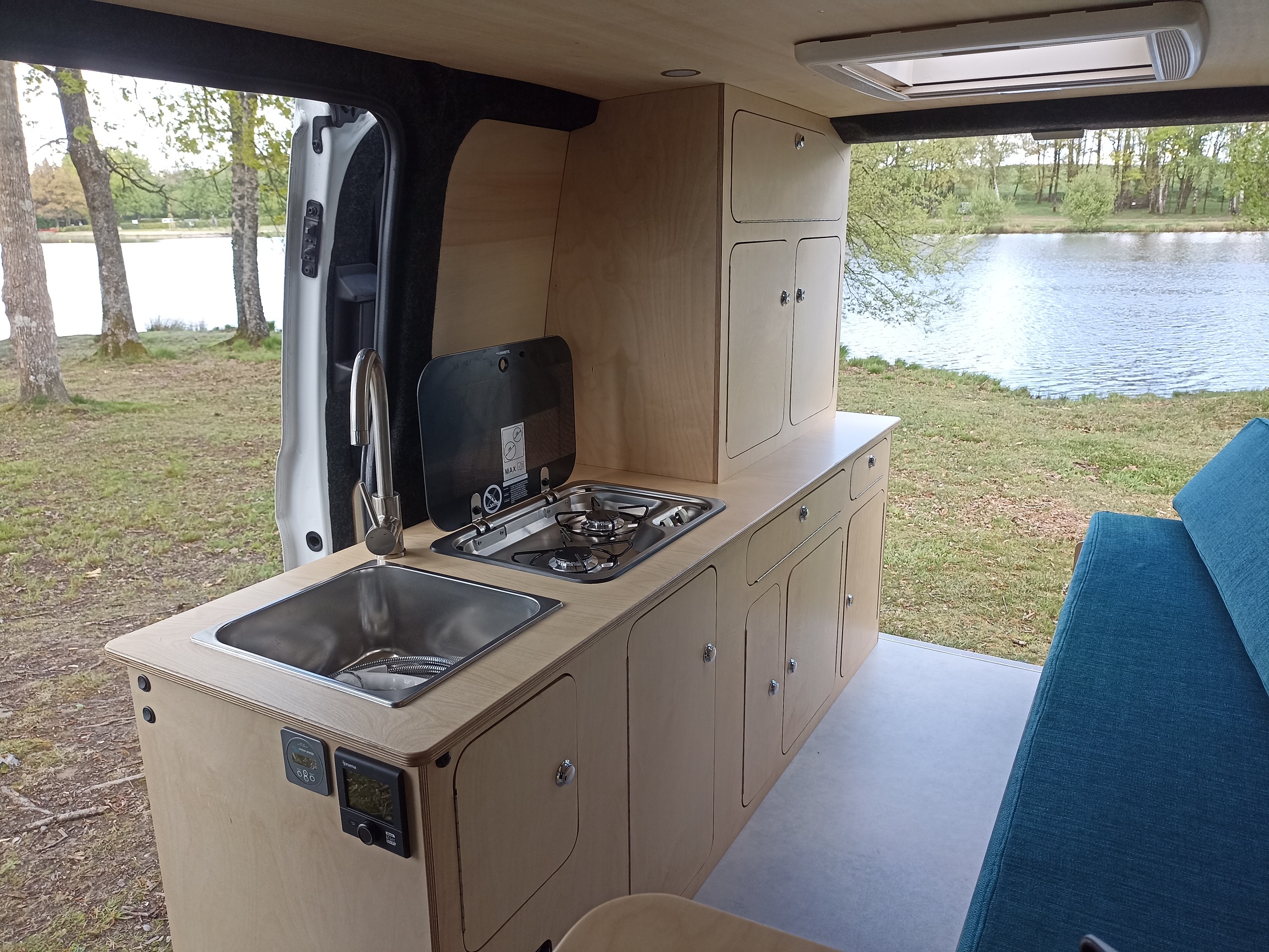 Van aménagé sur mesure en bois (contreplaqué) avec couloir de circulation entre la porte latérale et le coffre