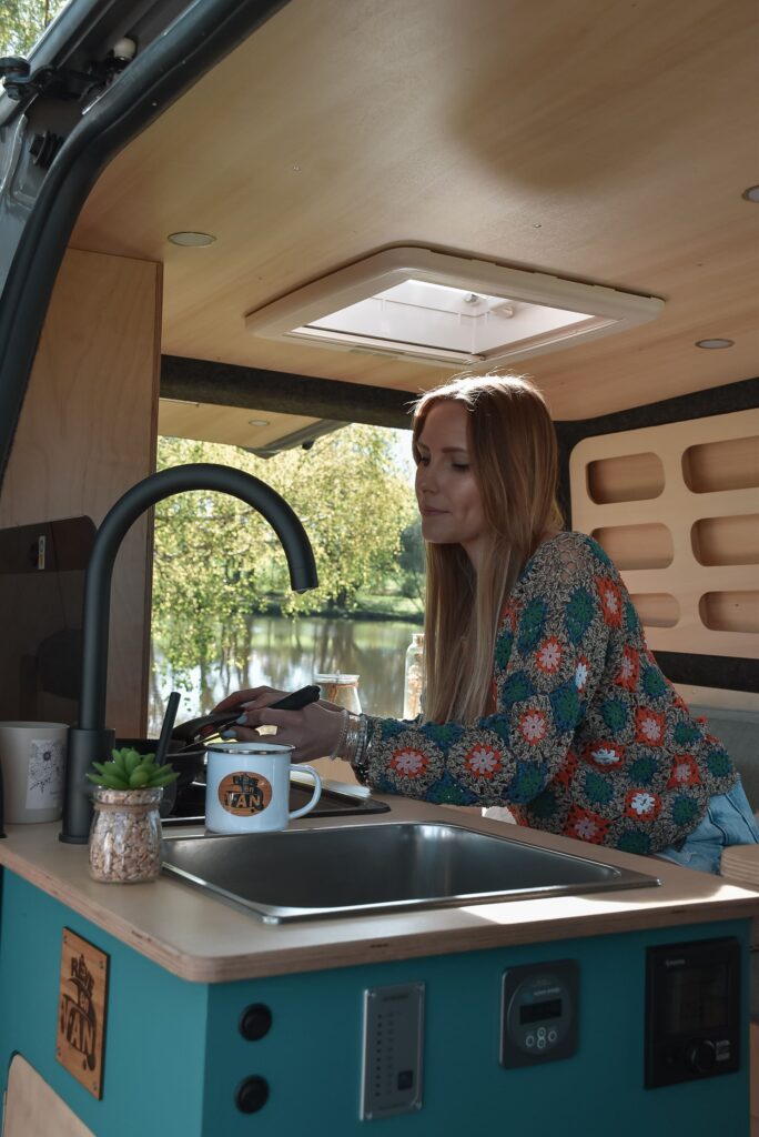 Van aménagé avec cuisine équipée d'une plaque de cuisson, d'un évier, d'un frigo et d'une table