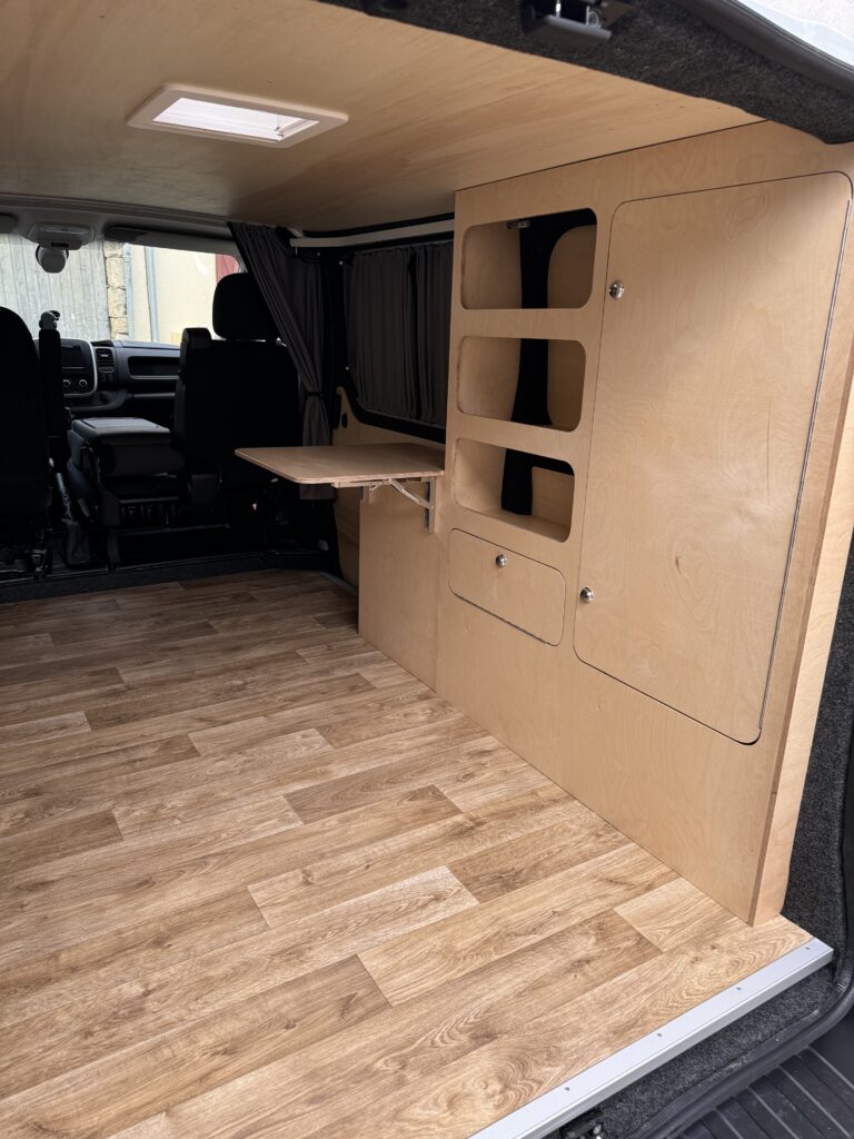 Mobilier sur mesure avec niches de rangement et tablette dans un van aménagé