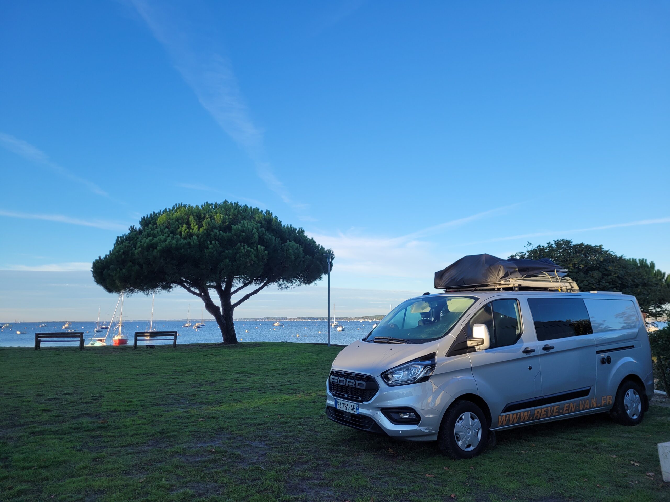 Ford Transit Custom transformé en aménagé avec tente de toit face à la mer